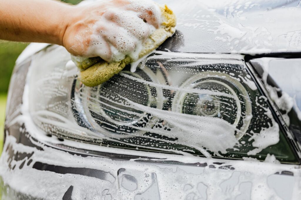 A Person Washing a the Headlight of a Car